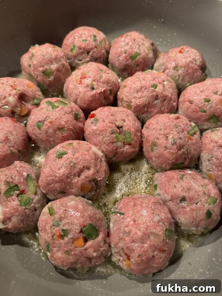 Raw Italian Beef meatballs beginning to cook