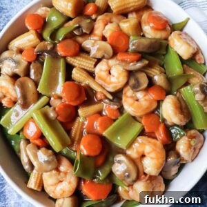 close up of shrimp chop suey in a white bowl with a blue background