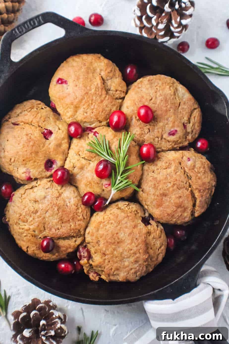 cranberry buttermilk biscuits topped with powdered sugar glaze in cast iron skillet garnished with fresh cranberries