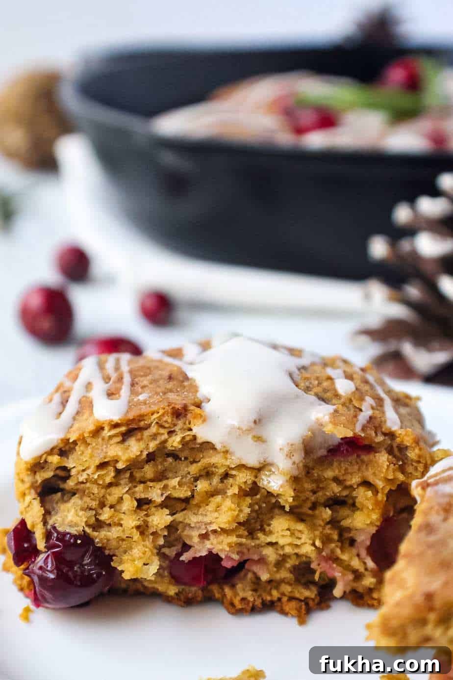 cranberry buttermilk biscuits topped with powdered sugar glaze in cast iron skillet garnished with fresh cranberries