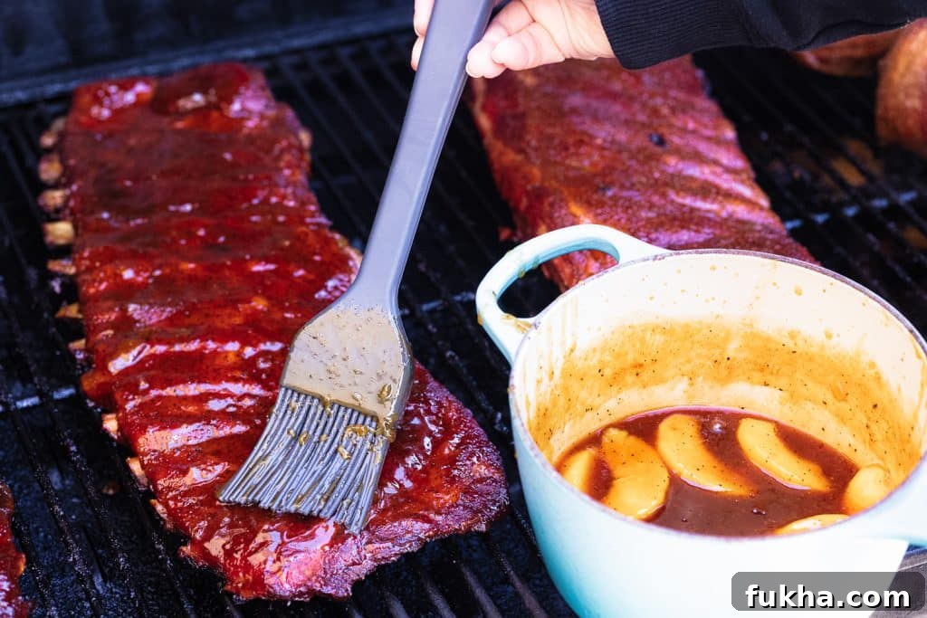 Fireball peach glaze being brushed on two racks of ribs.