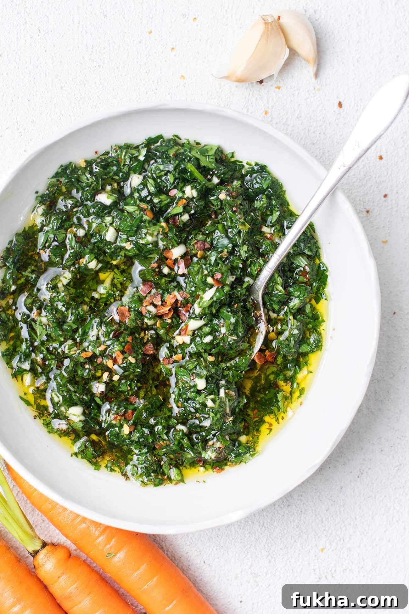 A close up look at a bowl of carrot top chimichurri garnished with red pepper flakes.