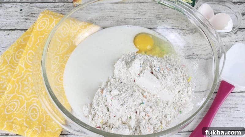 Large glass mixing bowl with buttermilk, pancake mix, and egg.