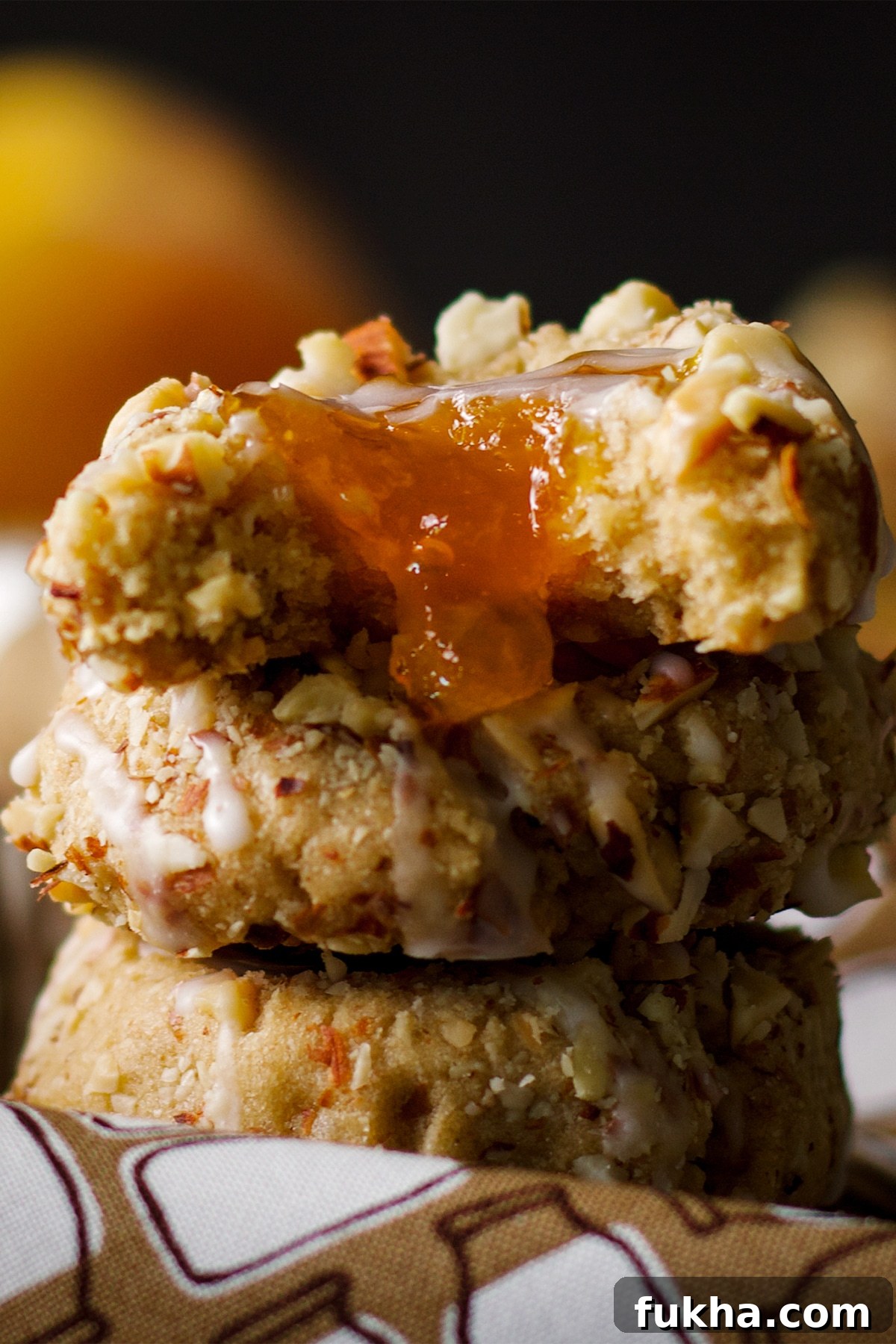 Stack of three almond thumbprint cookies filled with peach preserves.