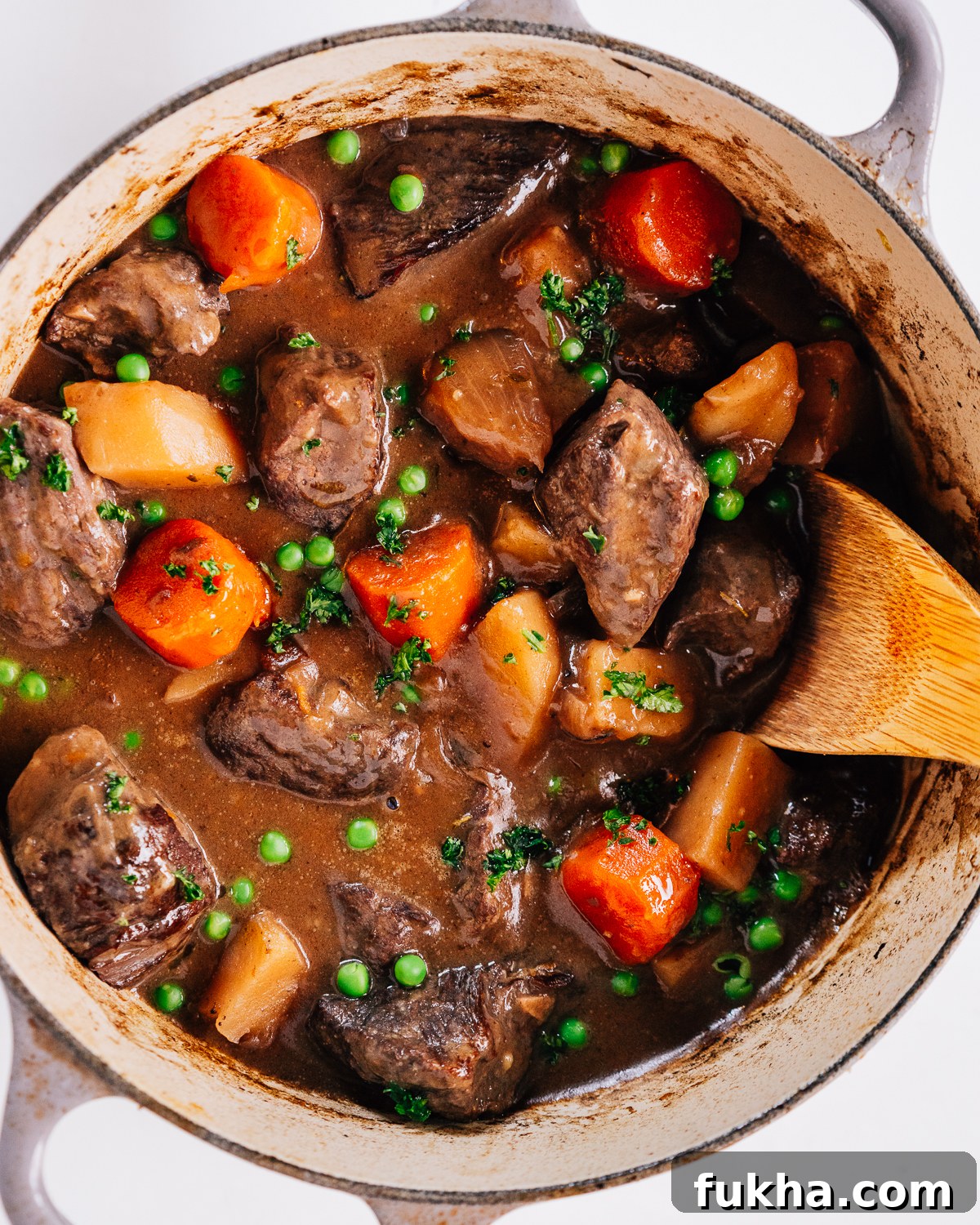 Dutch oven beef stew with a wooden spoon.