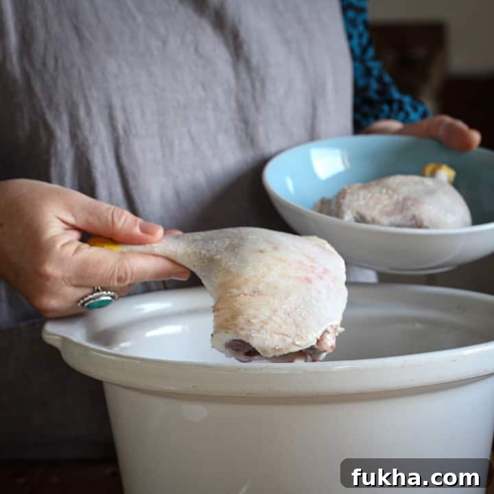 Woman placing uncooked duck leg into a white slow cooker