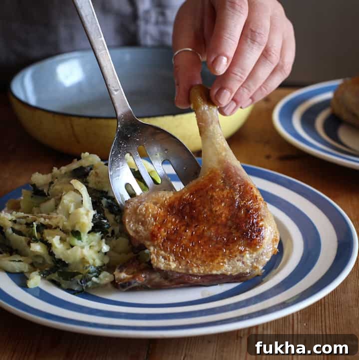 Womans hand dishing up crispy duck on a stripy blue and white plate