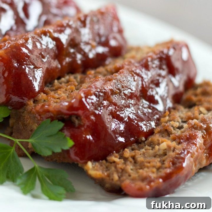 Slices of glazed meatloaf on a white plate.