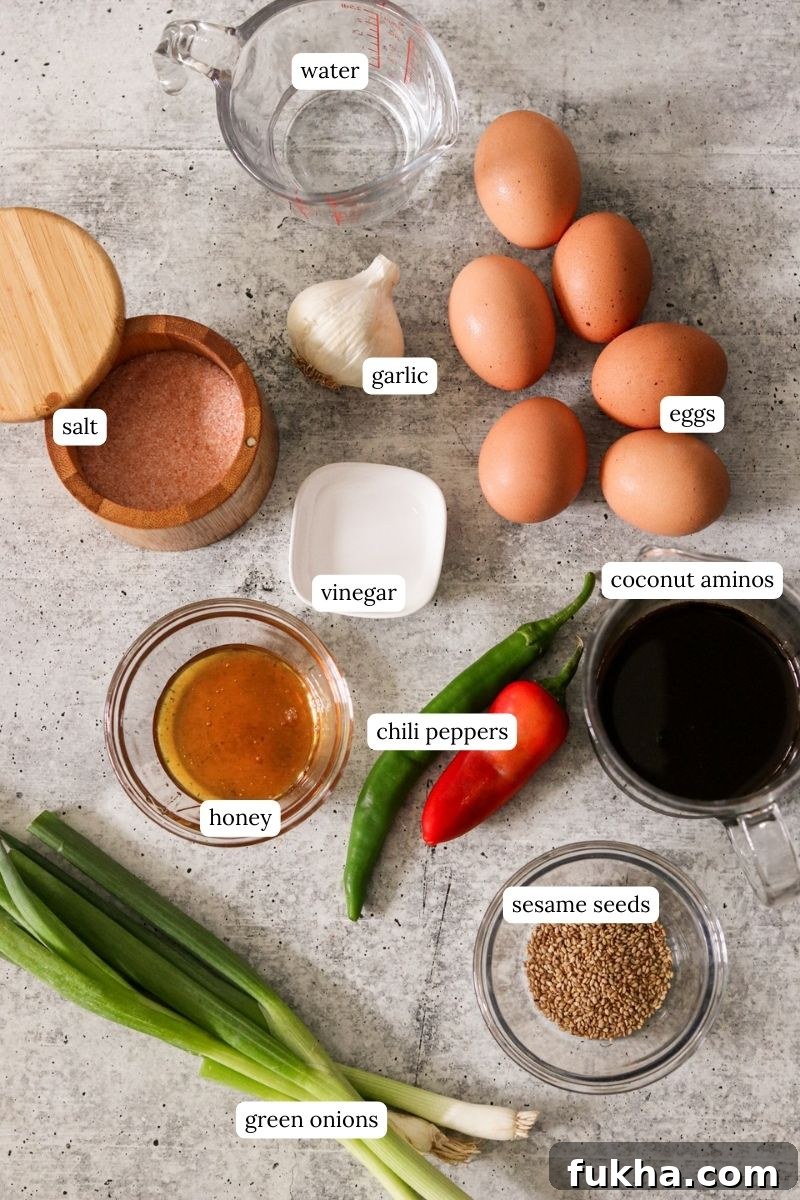 mayak eggs ingredients on a counter including honey, sesame seeds, coconut aminos, greens onions, chili peppers, salt, garlic, vinegar, and eggs.