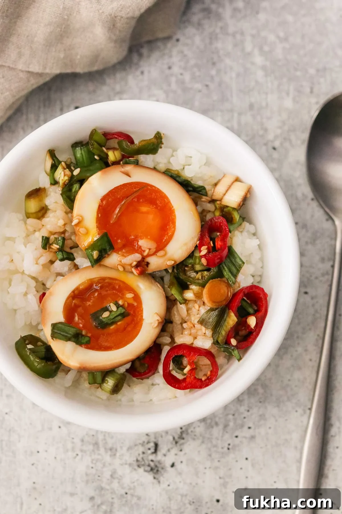 two marinated mayak eggs served over rice in a white bowl