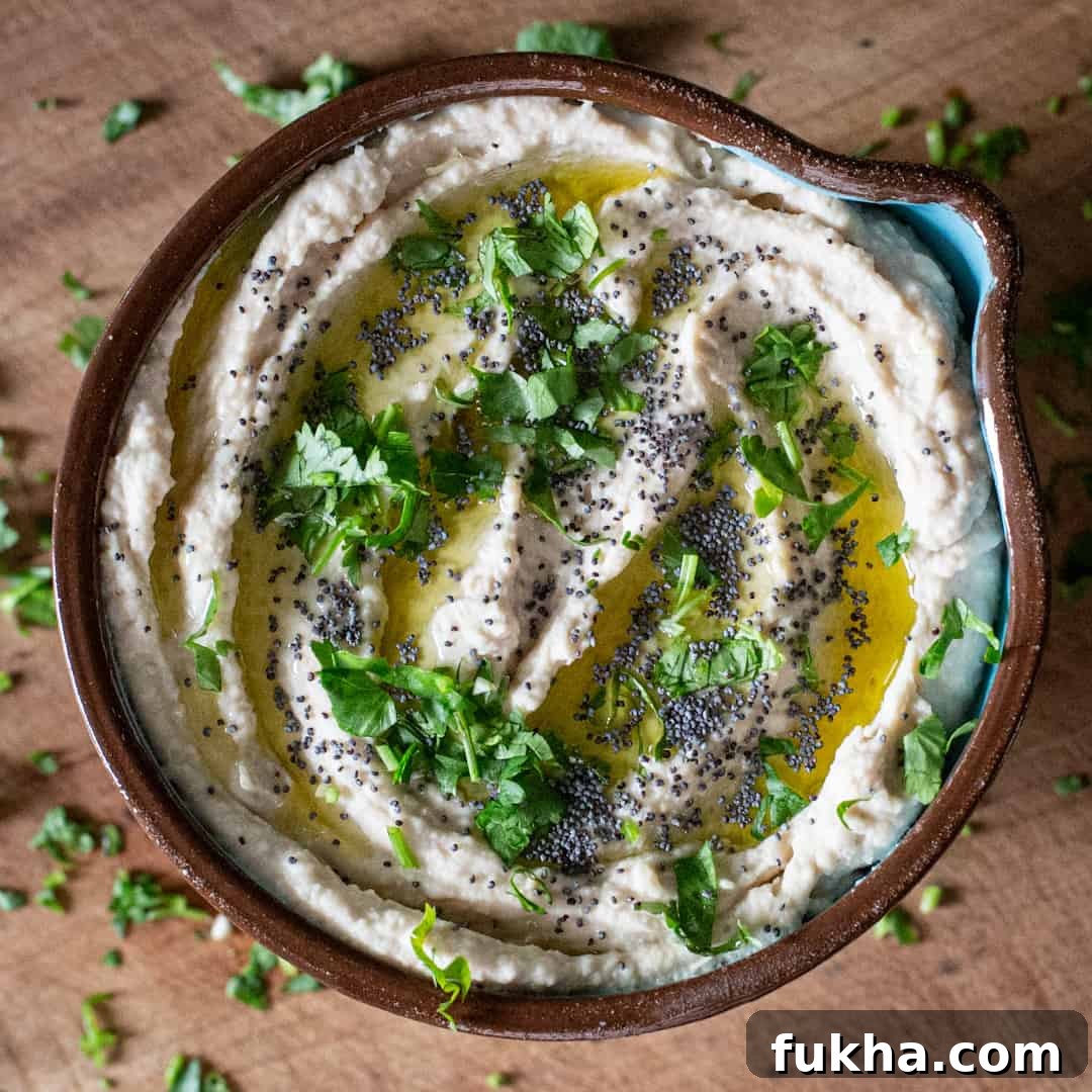 Overhead shot of creamy bean dip in brown bowl on wooden chopping board