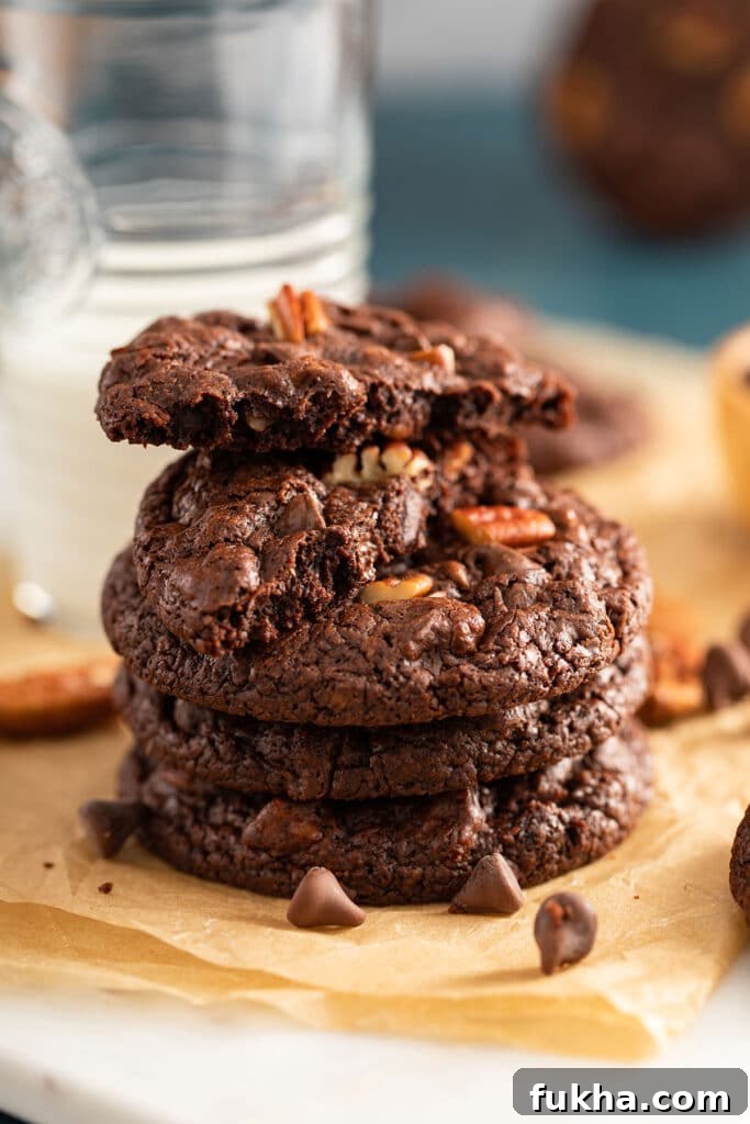 Stack of double chocolate cookies with chocolate chips and pecans.