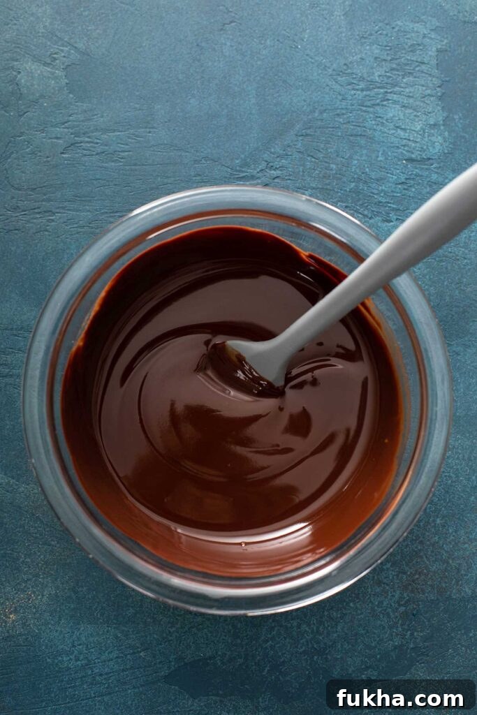 melted chocolate and butter in a clear mixing bowl with a gray spatula