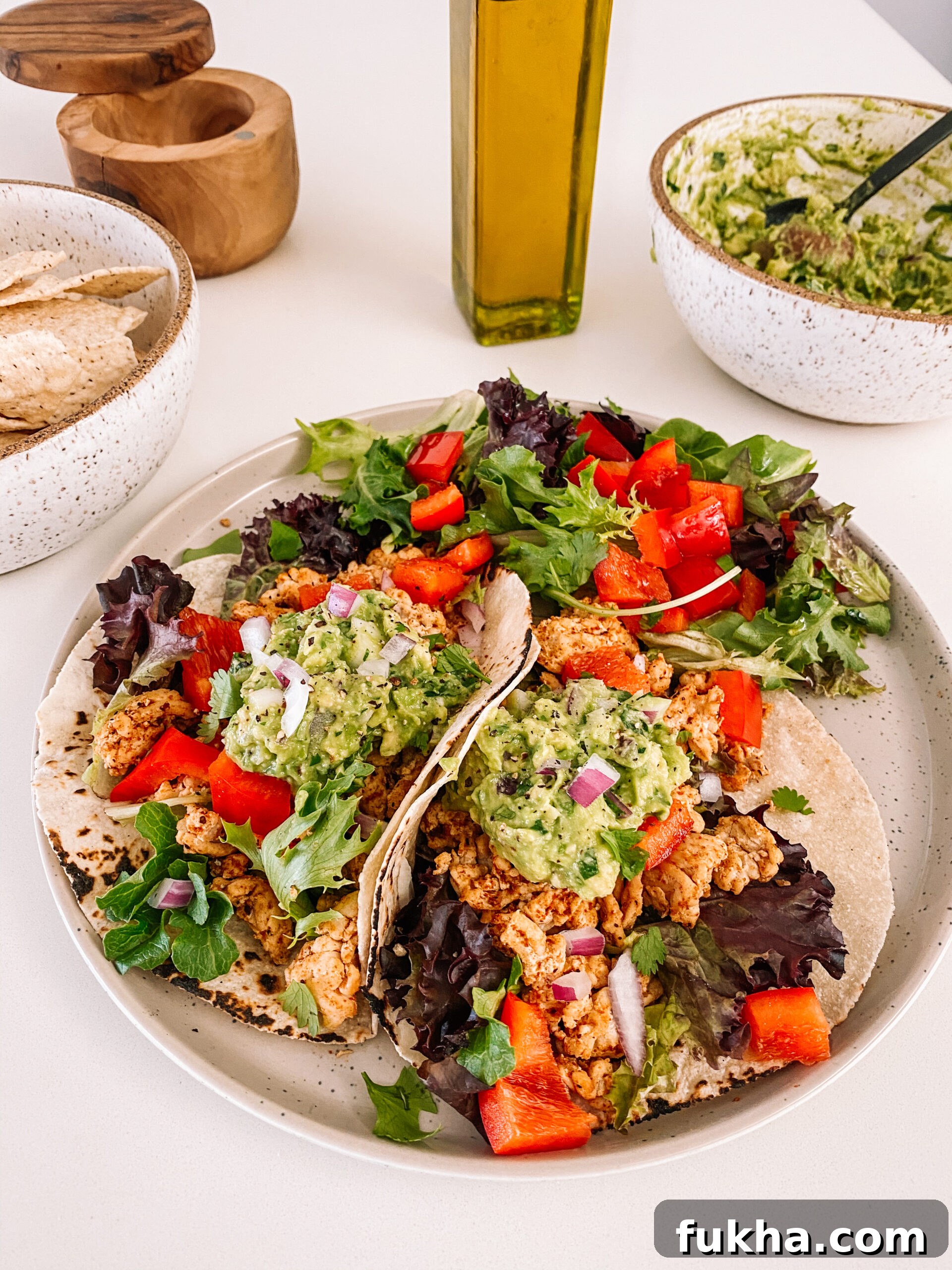 A plate of tacos with guacamole and mixed greens