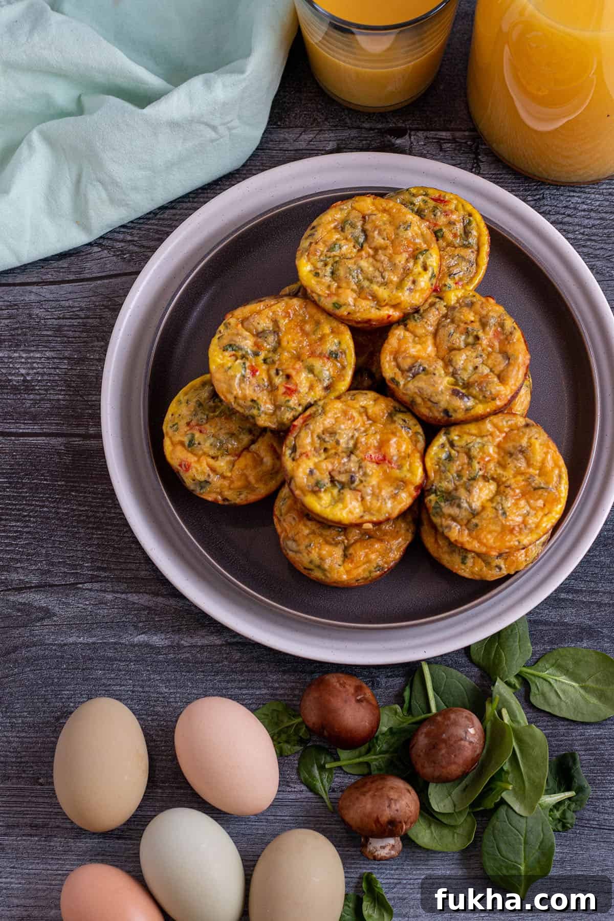 Sourdough Starter Breakfast Bites Recipe 9 A plate of sourdough breakfast bites on a plate with orange juice in the back and a cloth napkin and fresh ingredients.