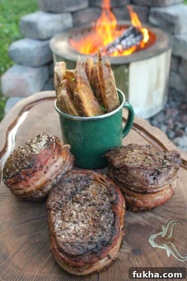 Bacon Wrapped Filets with Bacon Fat Fries sitting on a cutting board so that we can slice and serve them.