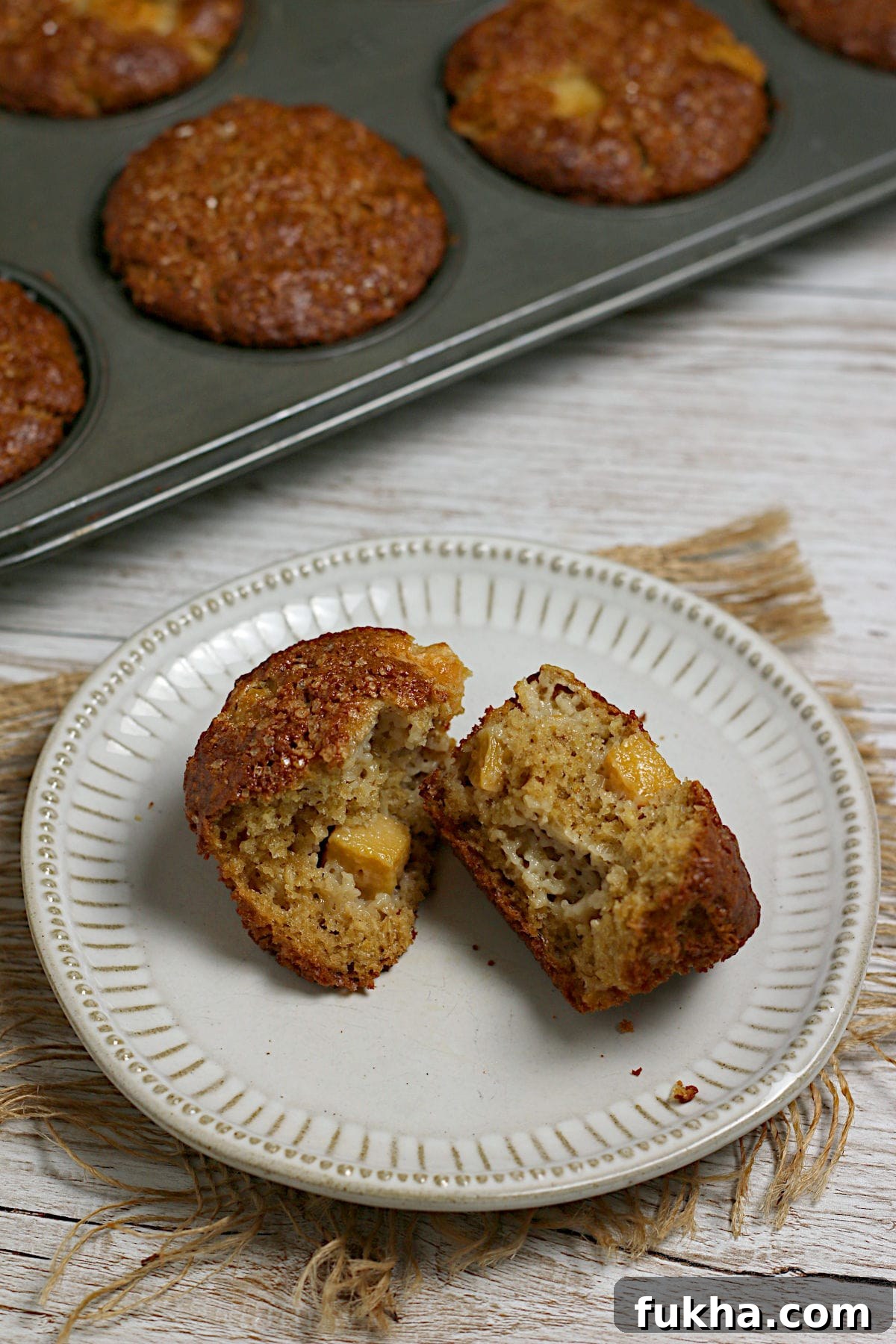 A Peaches and Cream Oatmeal Muffin broken in half on a small white plate.