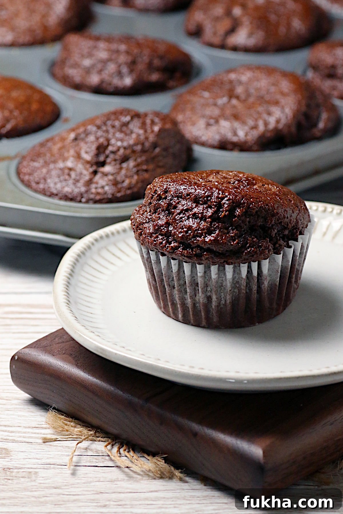 A double chocolate oatmeal muffin on a small white plate.