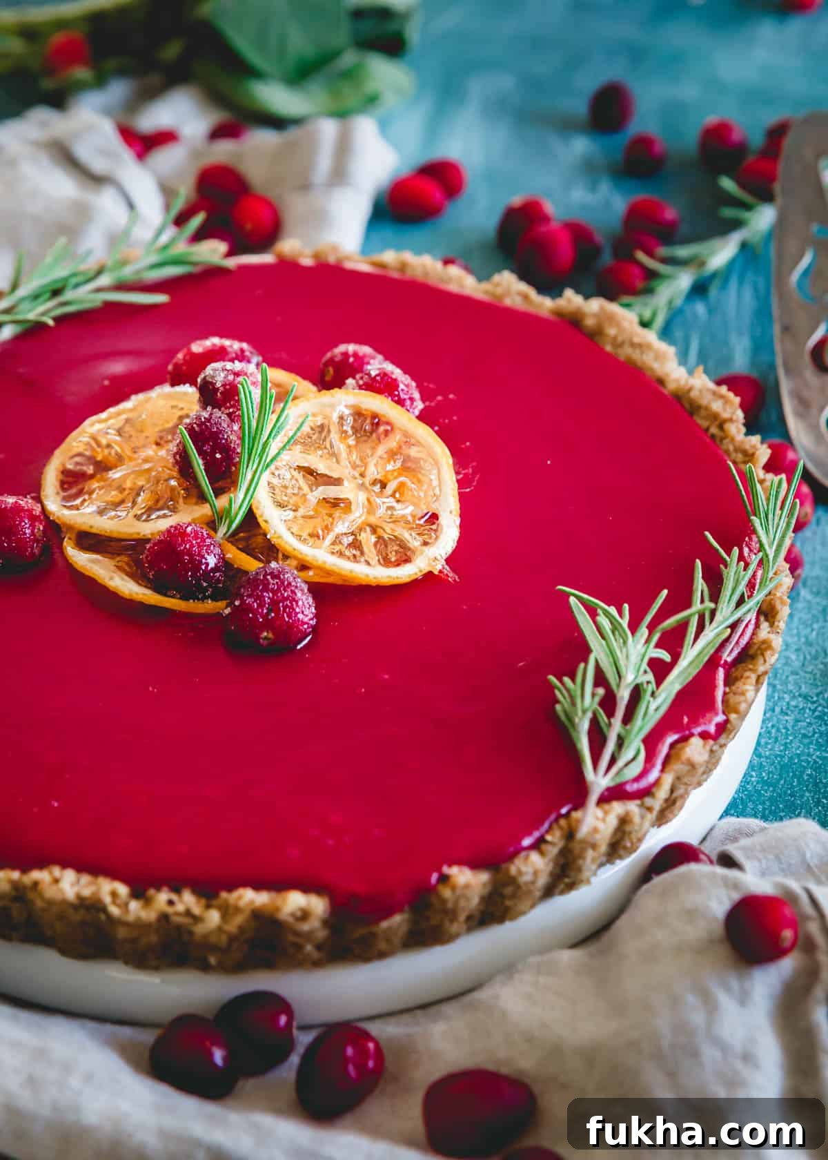 Cranberry curd tart garnished with sugared cranberries and candied lemon slices.