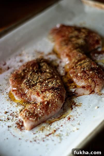 seasoned raw white fish on a baking sheet