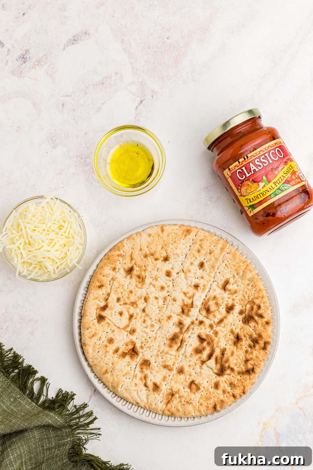 Make Crispy Air Fryer Pita Pizzas in 10 Minutes 3 Ingredients needed to make air fryer pita pizza on a marble table.