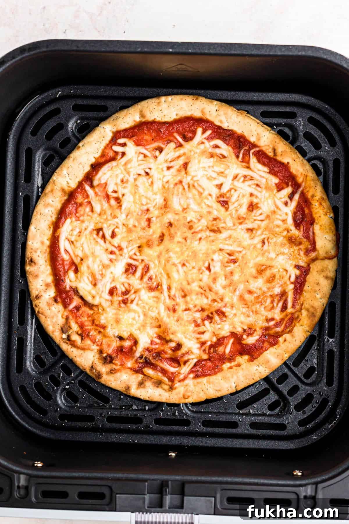 Make Crispy Air Fryer Pita Pizzas in 10 Minutes 6 Crispy pita pizza with golden brown crust in the air fryer basket.