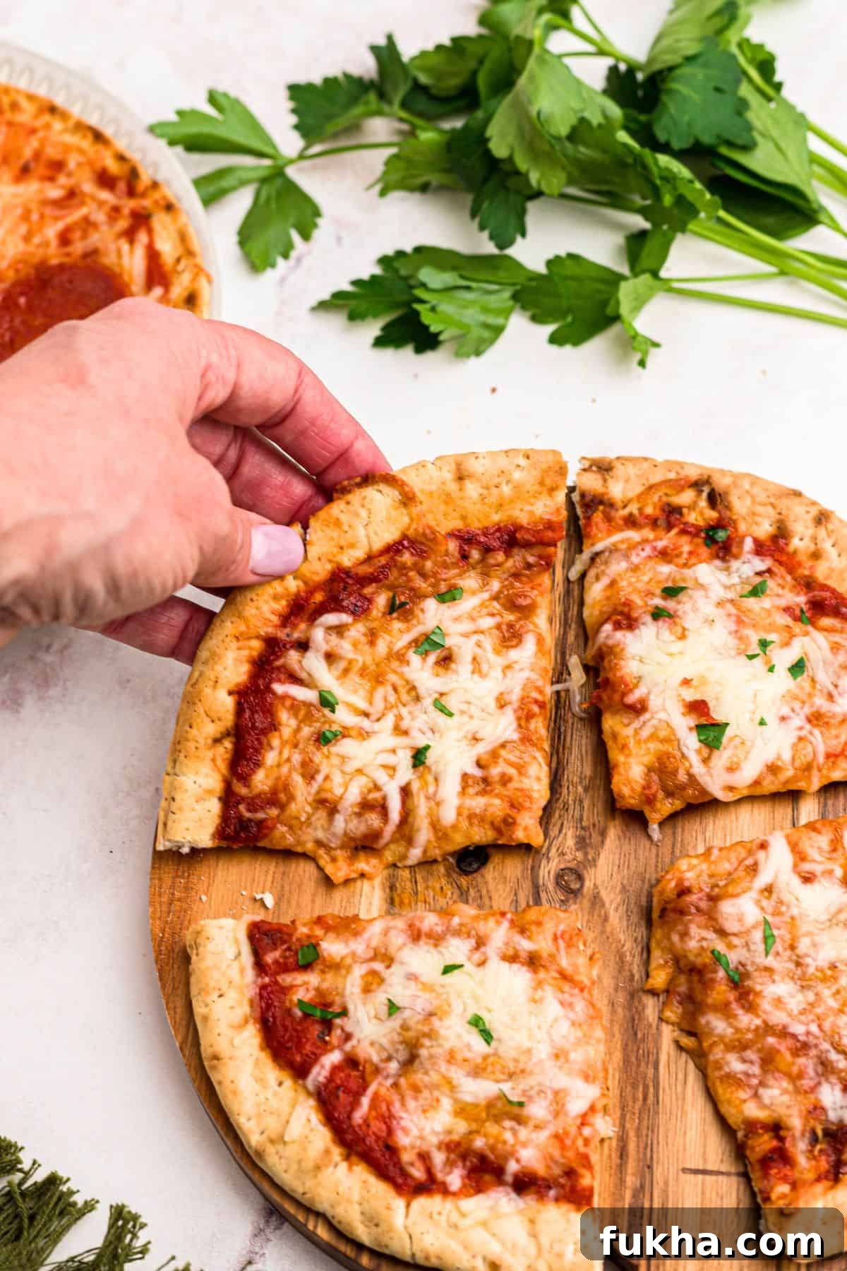 Make Crispy Air Fryer Pita Pizzas in 10 Minutes 7 Slice of pita pizza being lifted off of cutting board on a marble table.