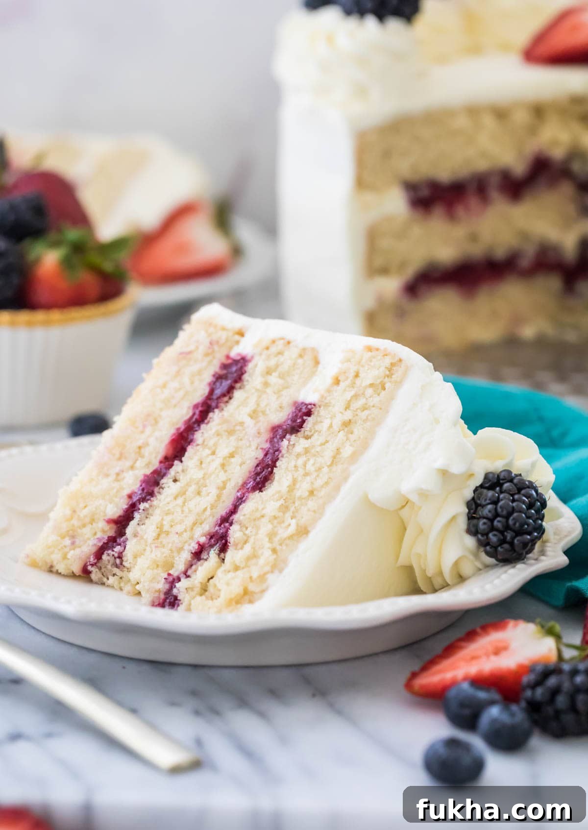 Decadent Chantilly Cream Cake Recipe 2 Three layer chantilly cake with berry filling on white plate surrounded by fruit and more cake