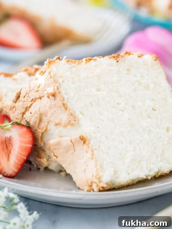Decadent Chantilly Cream Cake Recipe 13 Two slices of angel food cake on a white plate next to strawberries