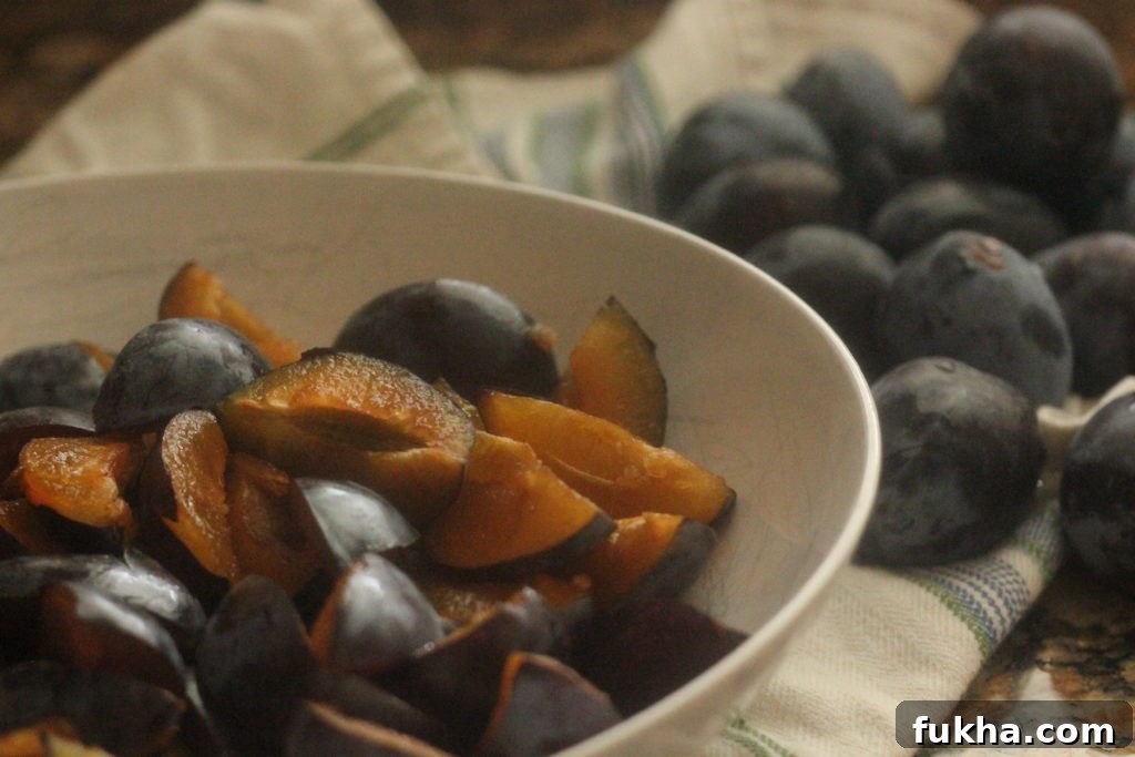 italian plums cut into quarters in a white bowl