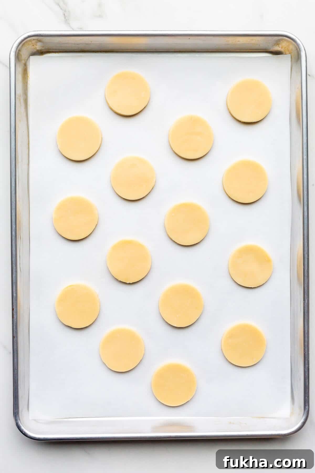 Classic Argentinian Alfajores Recipe with Dulce de Leche 6 Shortbread cookie cutouts before baking on a sheet pan lined with parchment.