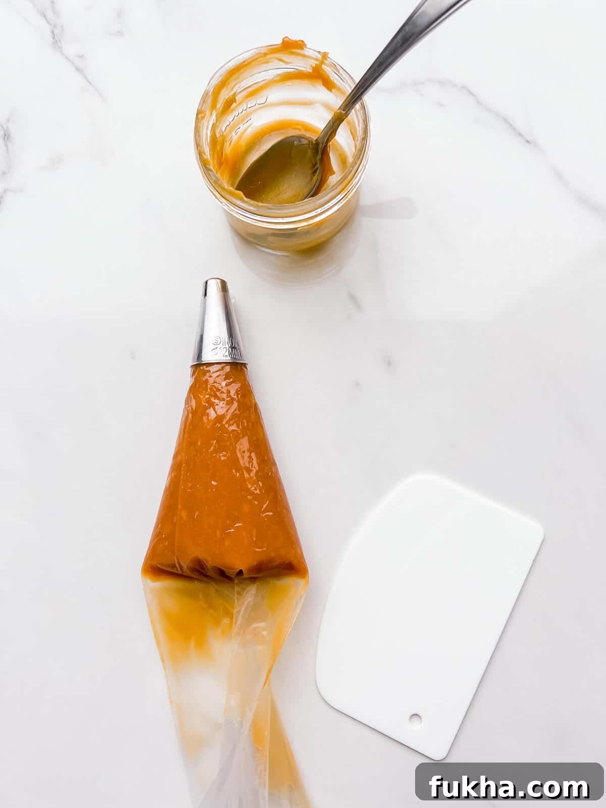 Classic Argentinian Alfajores Recipe with Dulce de Leche 8 Filling a piping bag with dulce de leche and pushing the filling to the front of the bag with a bench scraper.