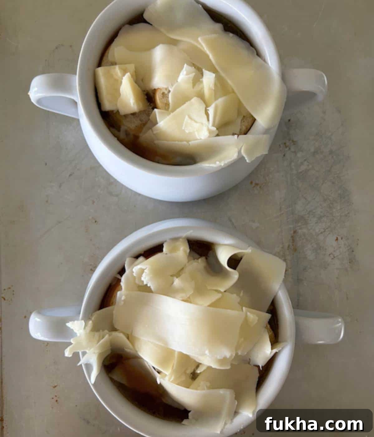 Two soup bowls full of French onion soup topped with bread and cheese.