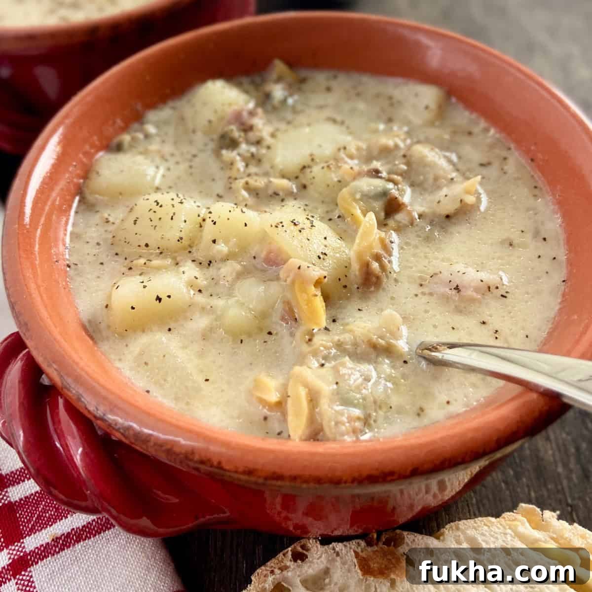 New England Clam Chowder in red bowl with spoon.