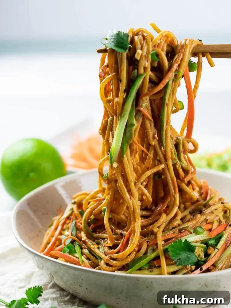 Thai peanut noodles in a bowl held by chopsticks