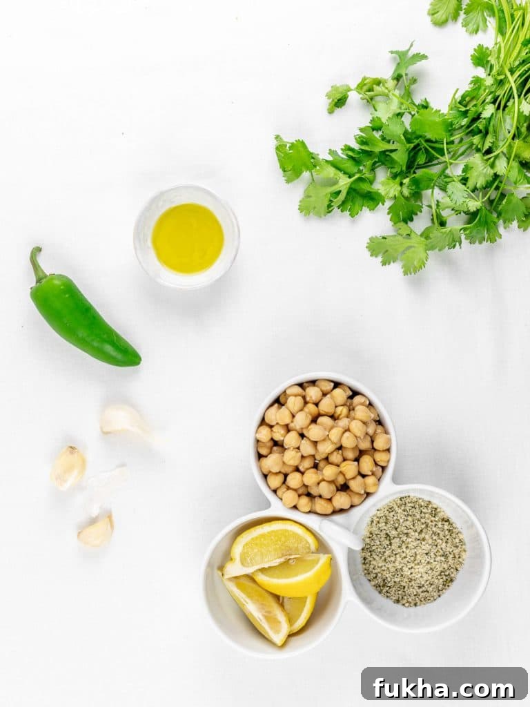 Tahini-Free Cilantro Jalapeno Hemp Seed Hummus 4 ingredients for cilantro jalapeno hemp seed hummus in a bowl with garlic and lemons