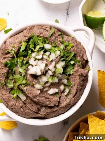bean dip in bowl with chips and lime on the side