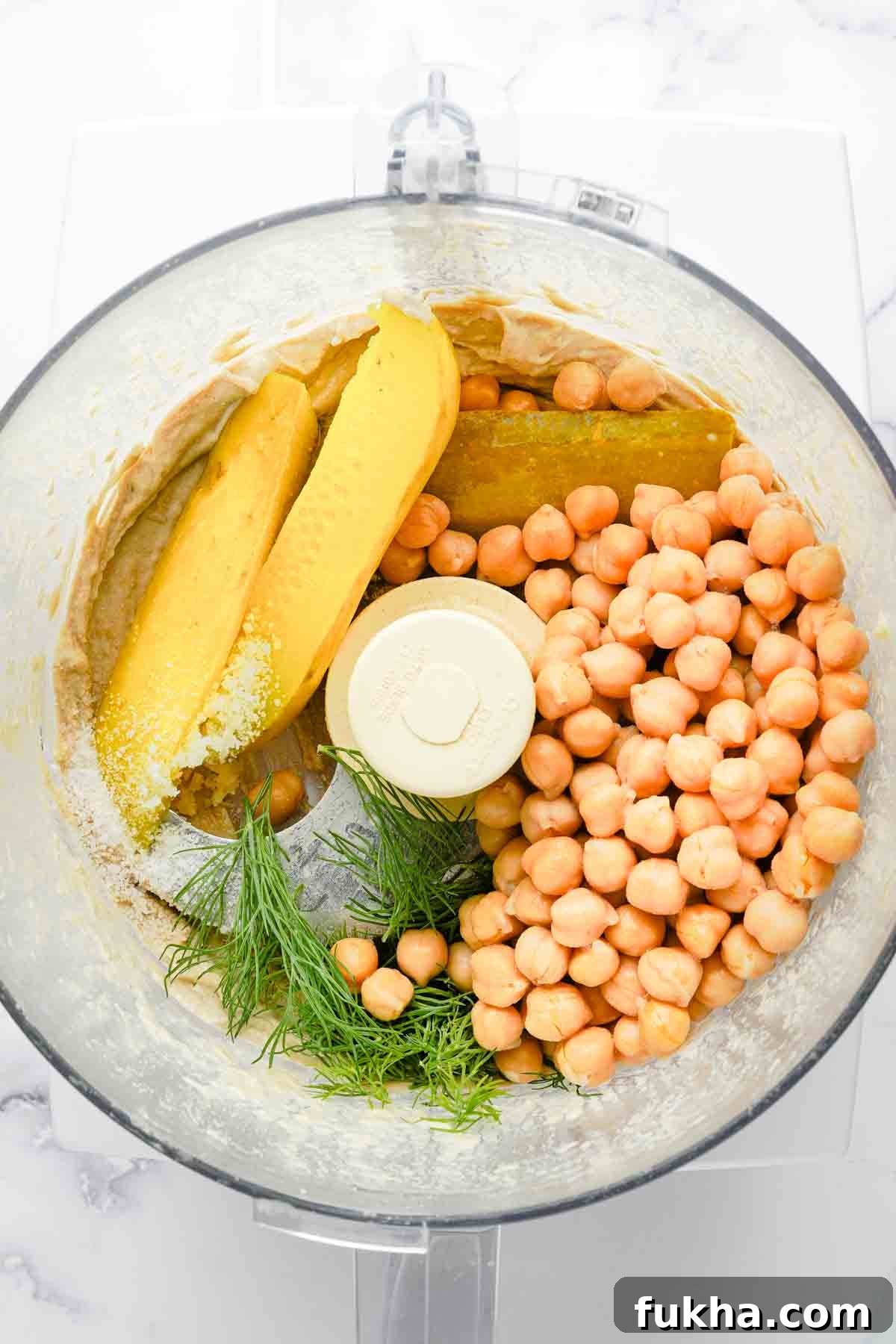 hummus ingredients in the bowl of a food processor.