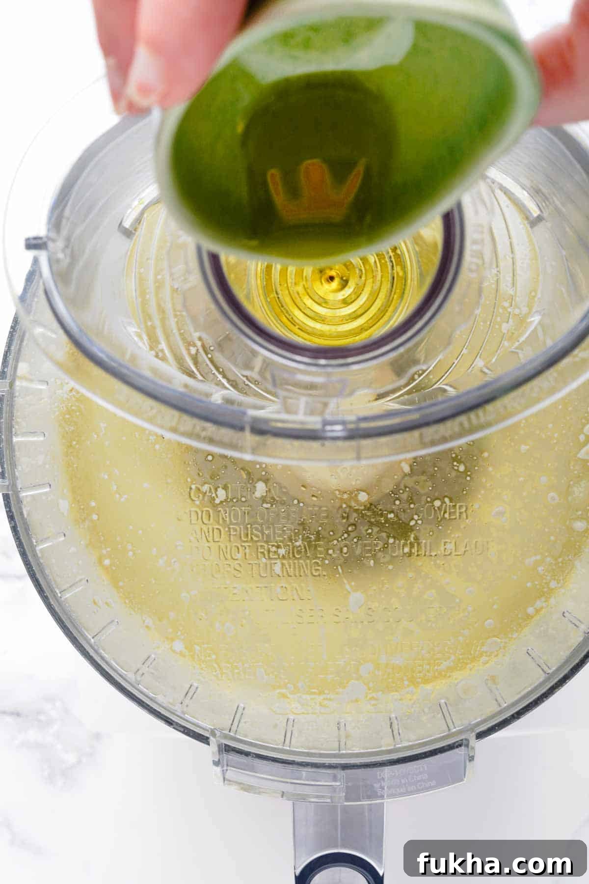 oil being drizzled into food processor.