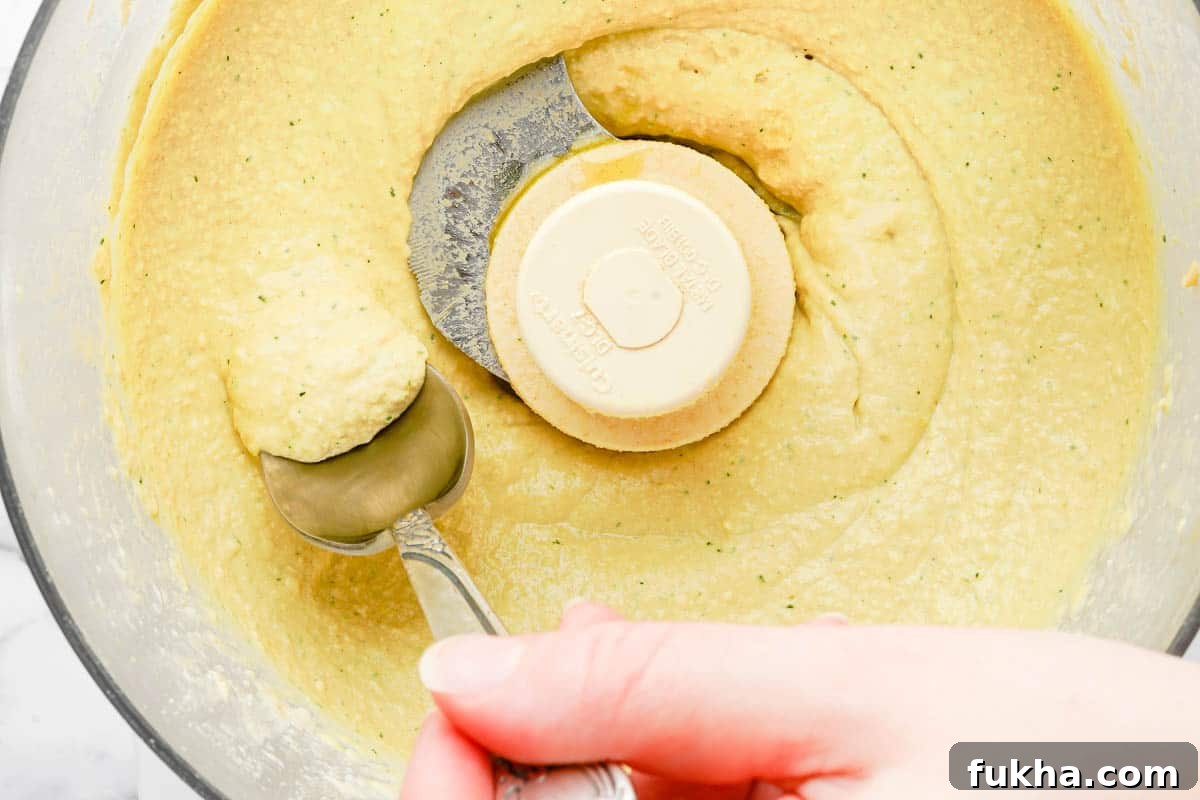 spoon scraping hummus out of food processor.