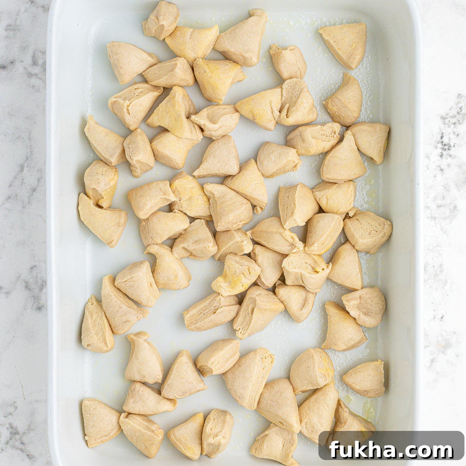 Pieces of chilled biscuits scattered in a casserole dish