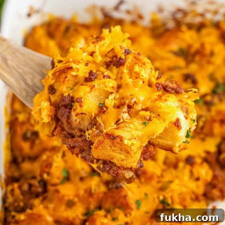 Taking a spoonful of sloppy joe bubble up casserole from the casserole dish