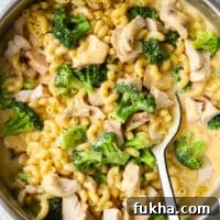 stirring chicken broccoli macaroni and cheese with a large spoon