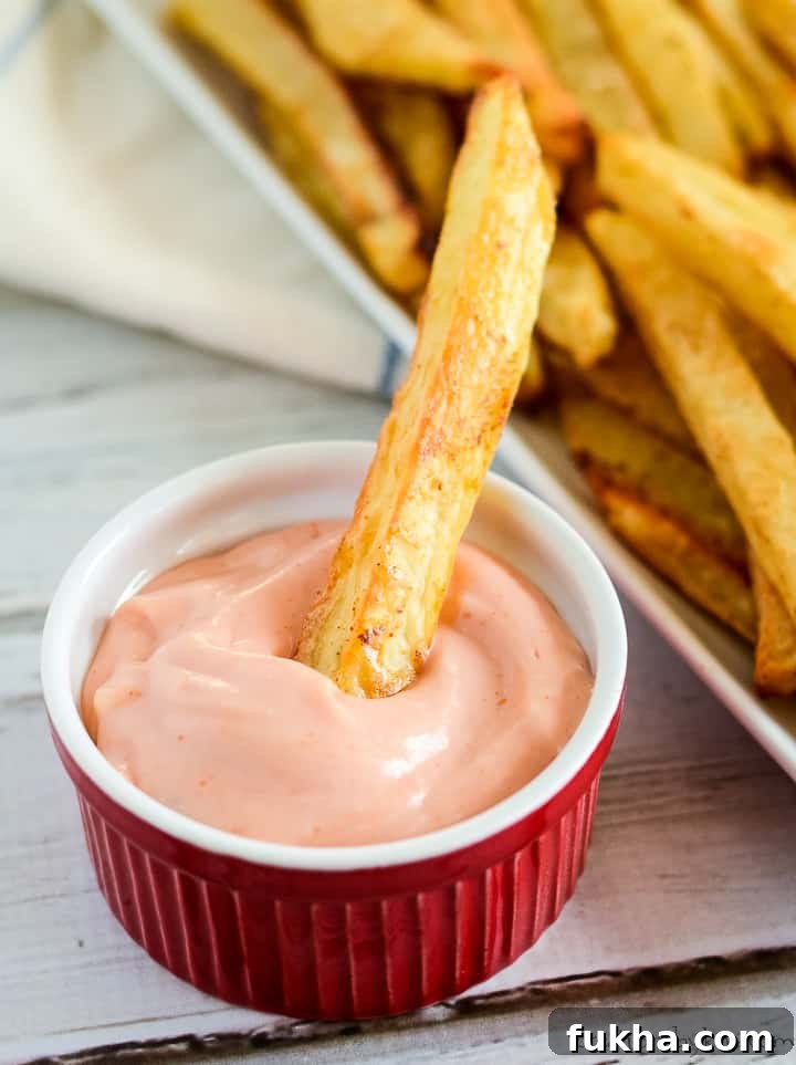 crispy oven baked fries, one being dipped in fry sauce