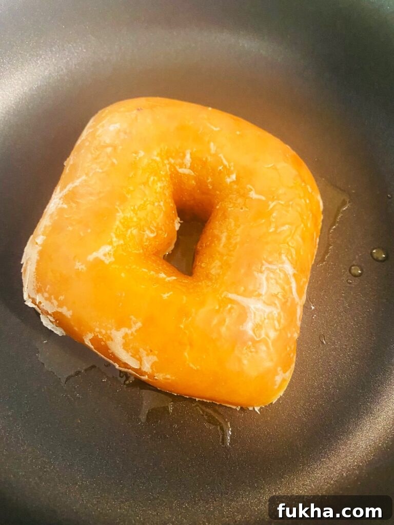 Donut with cheese and bacon in a skillet, cut side down