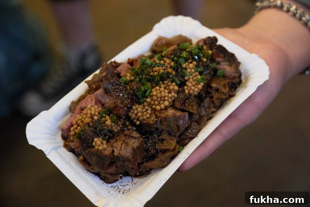 24-Hour Berlin Food Guide: What to Eat in a Day 4 A woman's hand holding a small plate of steak topped with mustard sauce.