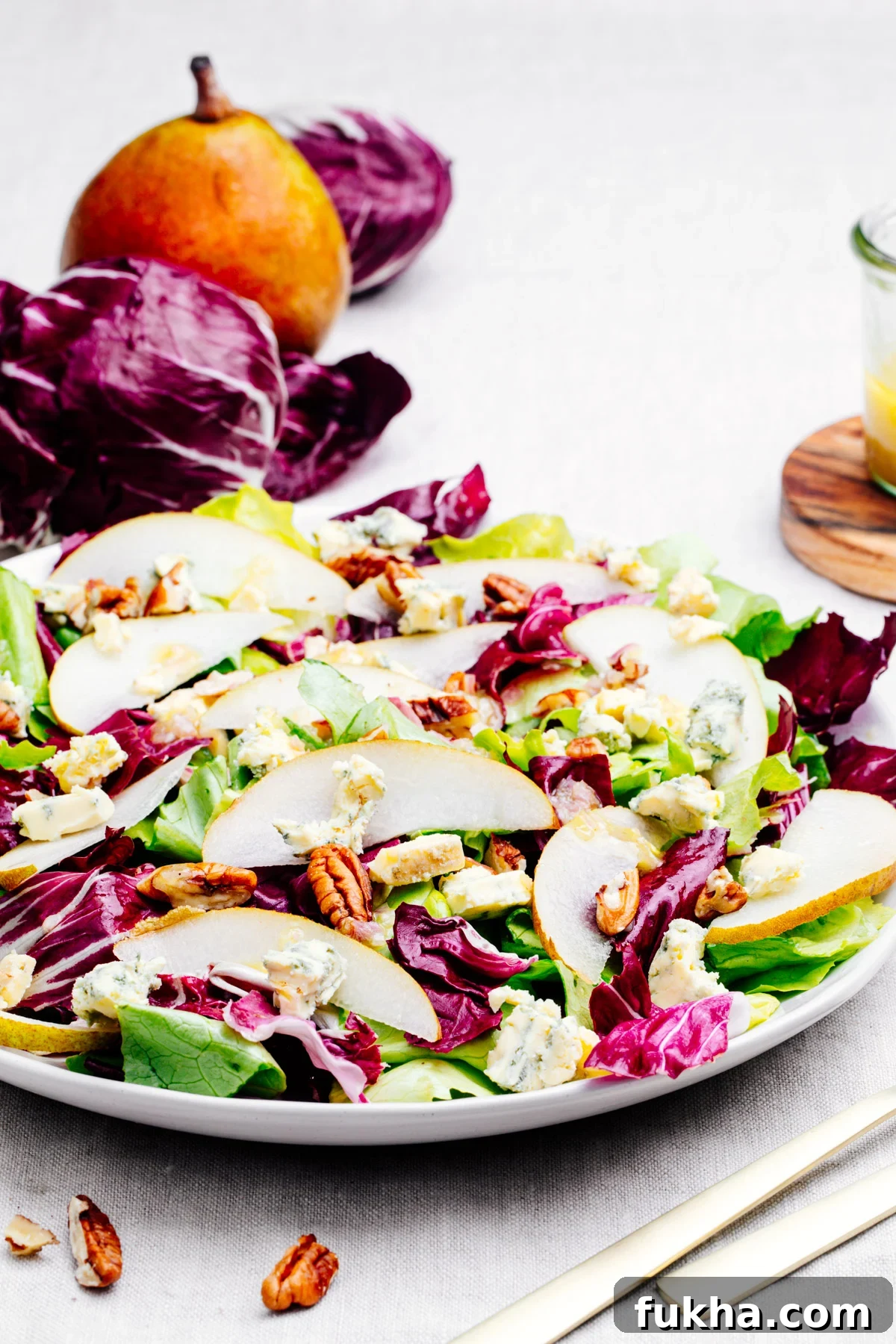 Radicchio Salad served on a white plate with radicchio and pear in the background.
