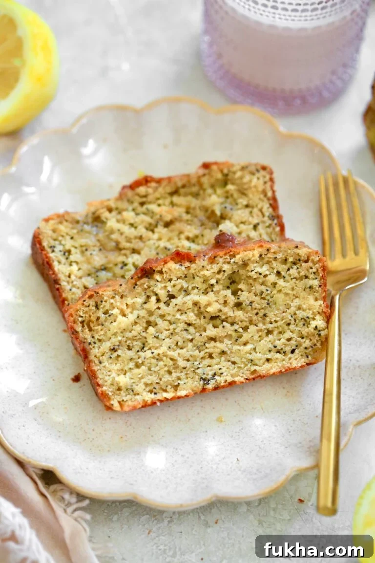 two slices lemon poppyseed bread on plate with gold fork.