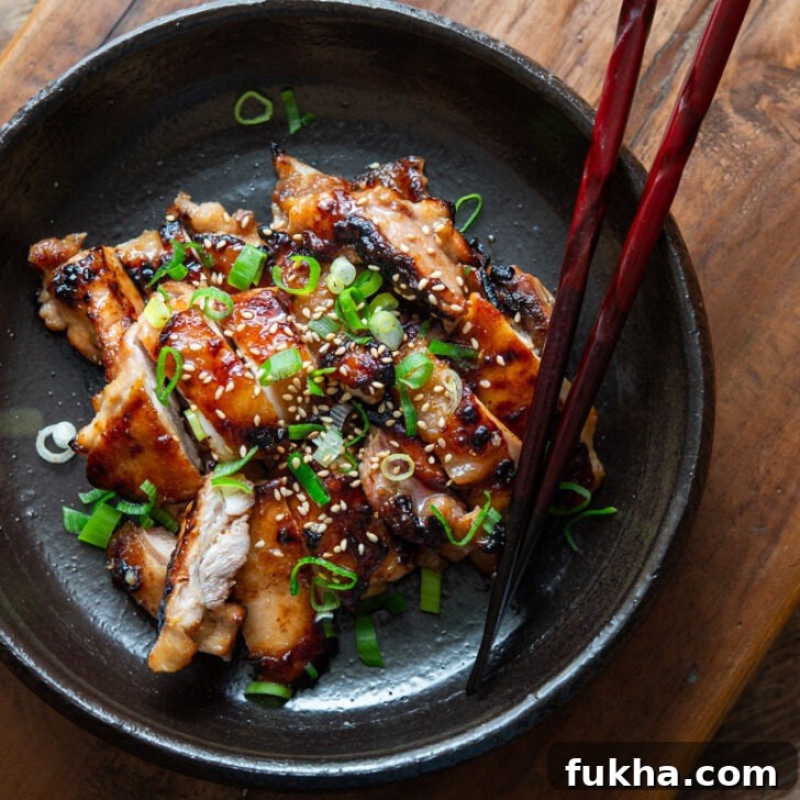 A plate of miso chicken thighs with chopsticks.