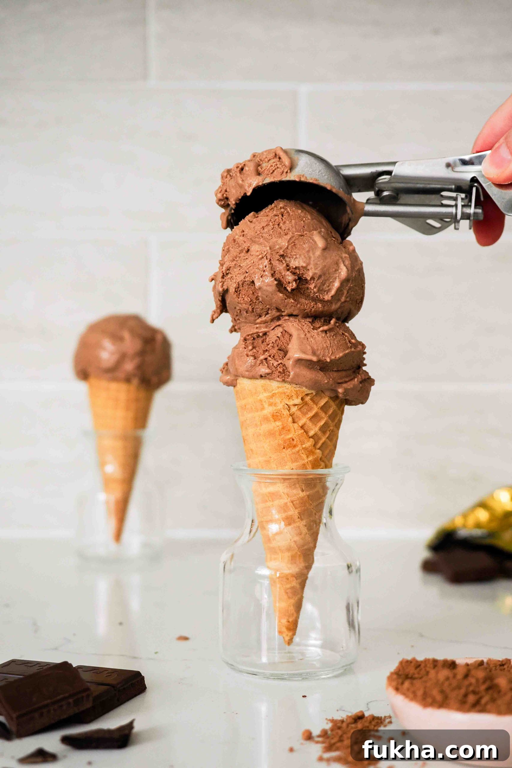 A second scoop of double chocolate ice cream is added to an ice cream cone.